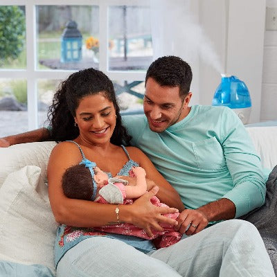 Papa y mama con bebe y humidificador en segundo plano